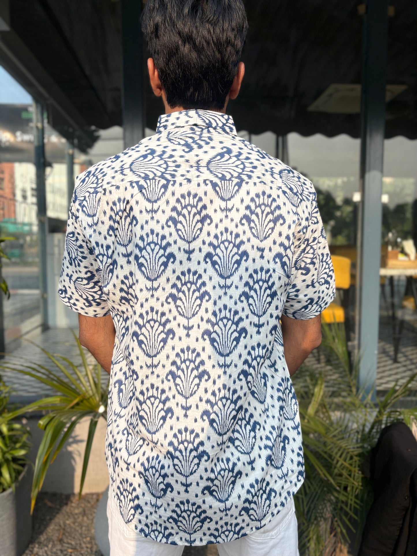 Person wearing white shirt with blue pattern outdoors
