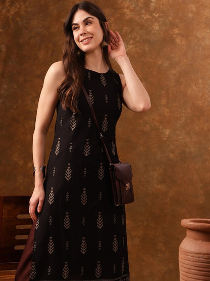 Woman wearing black patterned dress against brown wall