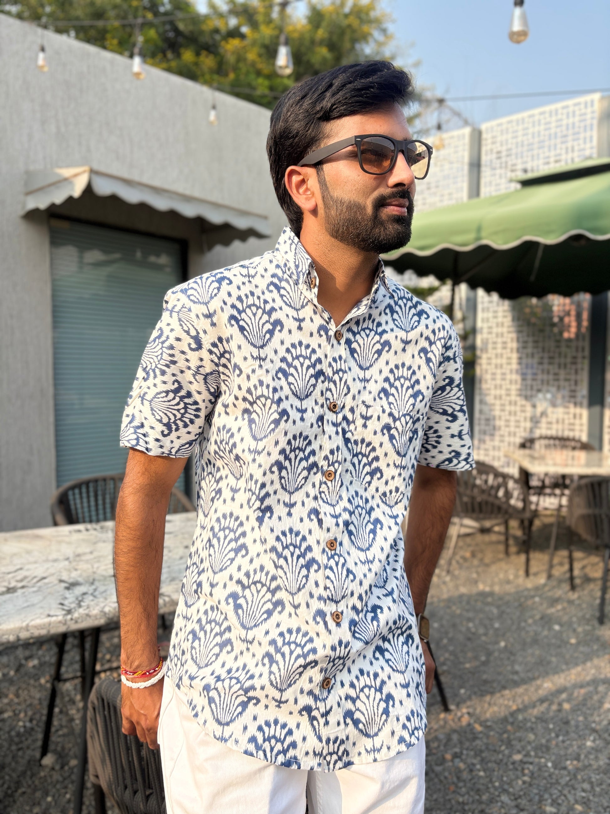 Man wearing patterned shirt outdoors near tables and chairs