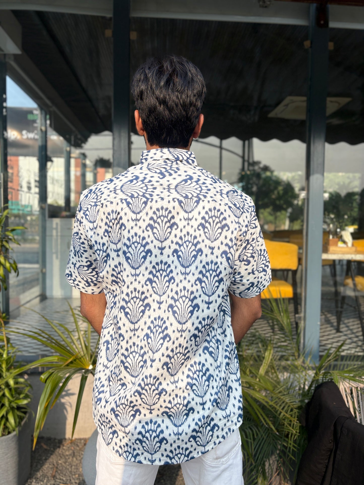 Person wearing white shirt with blue patterns outdoors