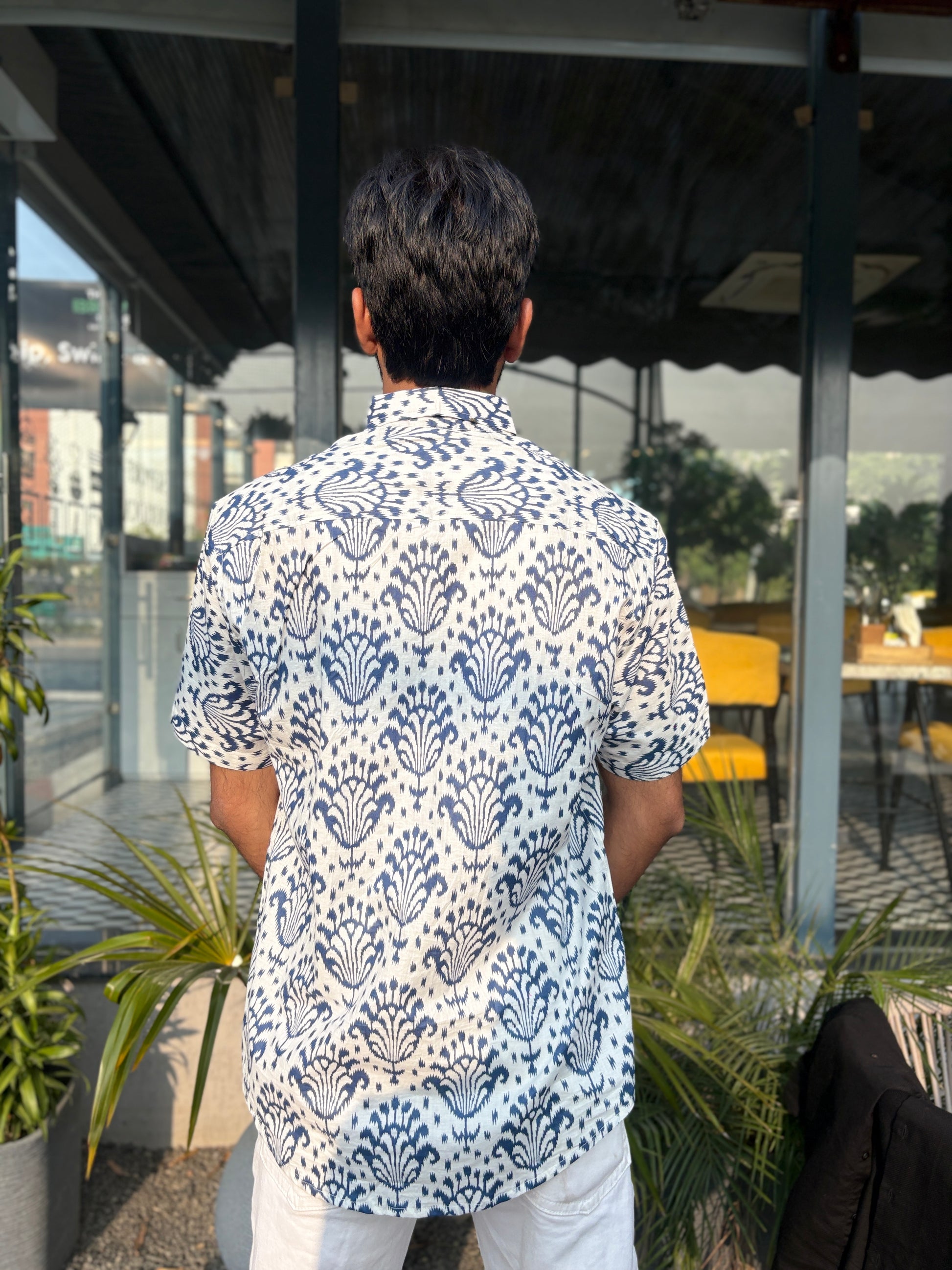 Person wearing white shirt with blue patterns outdoors