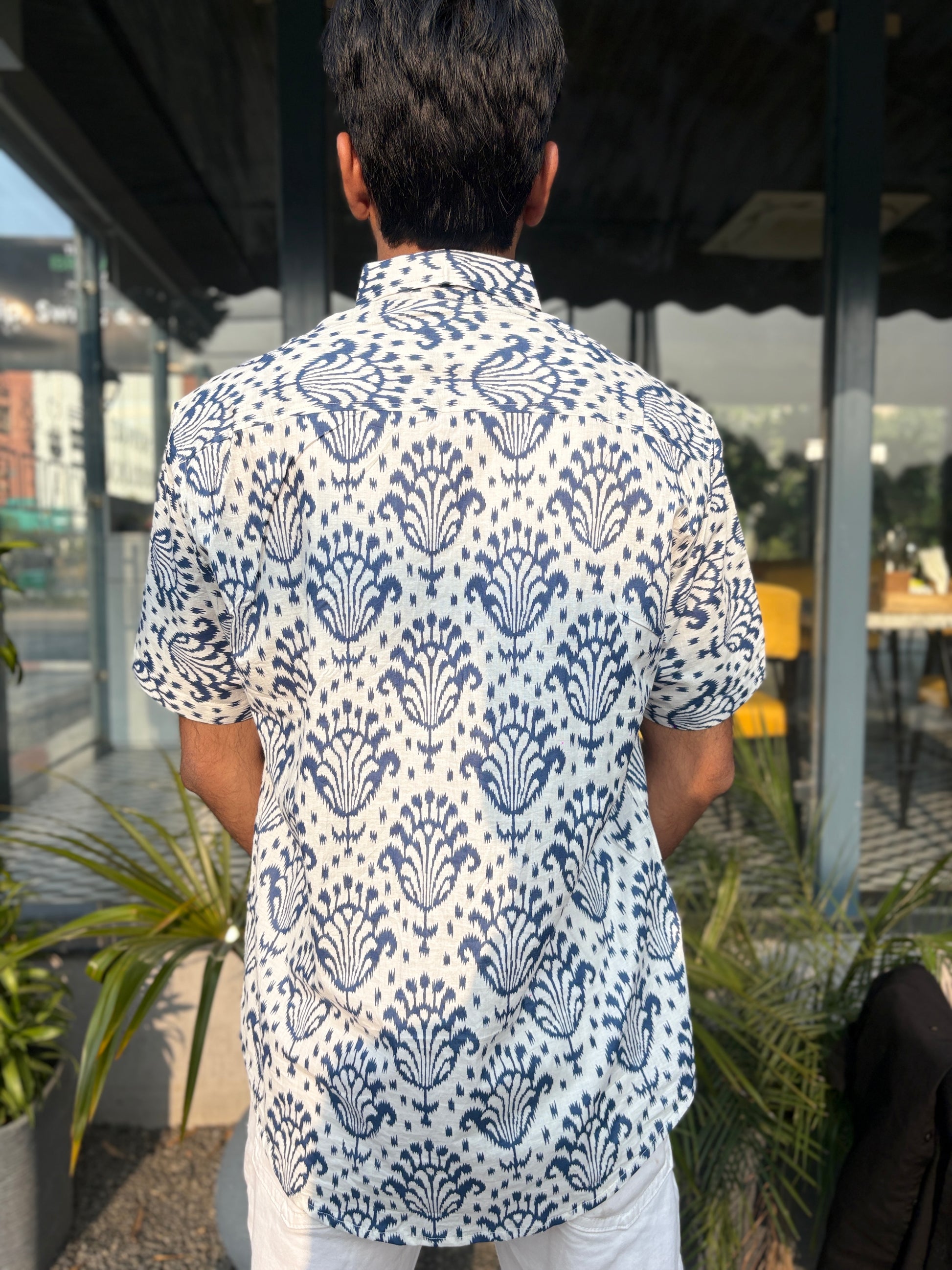 Person wearing white shirt with blue pattern outdoors