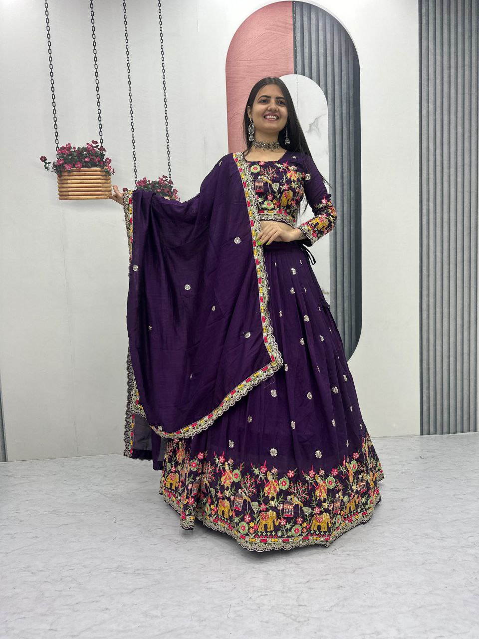 Woman in a purple traditional outfit with floral patterns standing in front of a mirror.